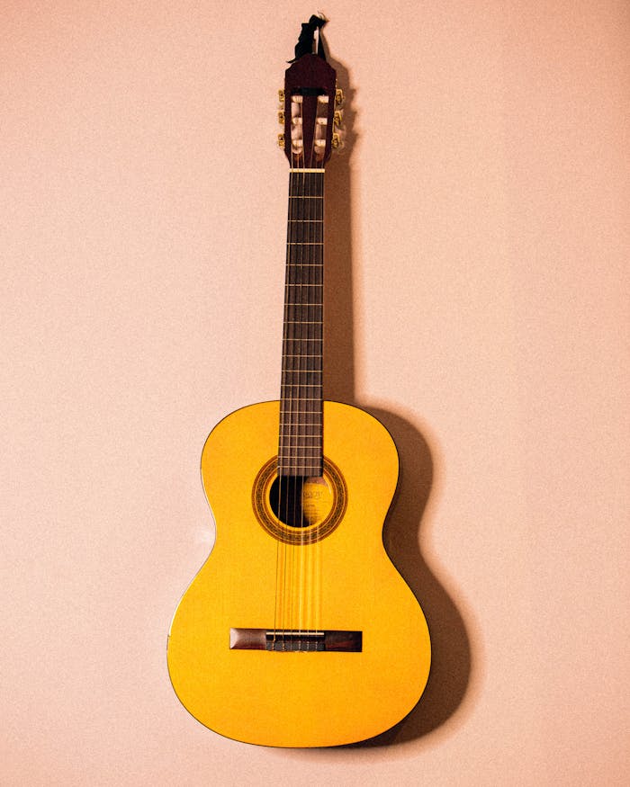 Yellow acoustic guitar hanging on a wall, showcasing its design and craftsmanship.